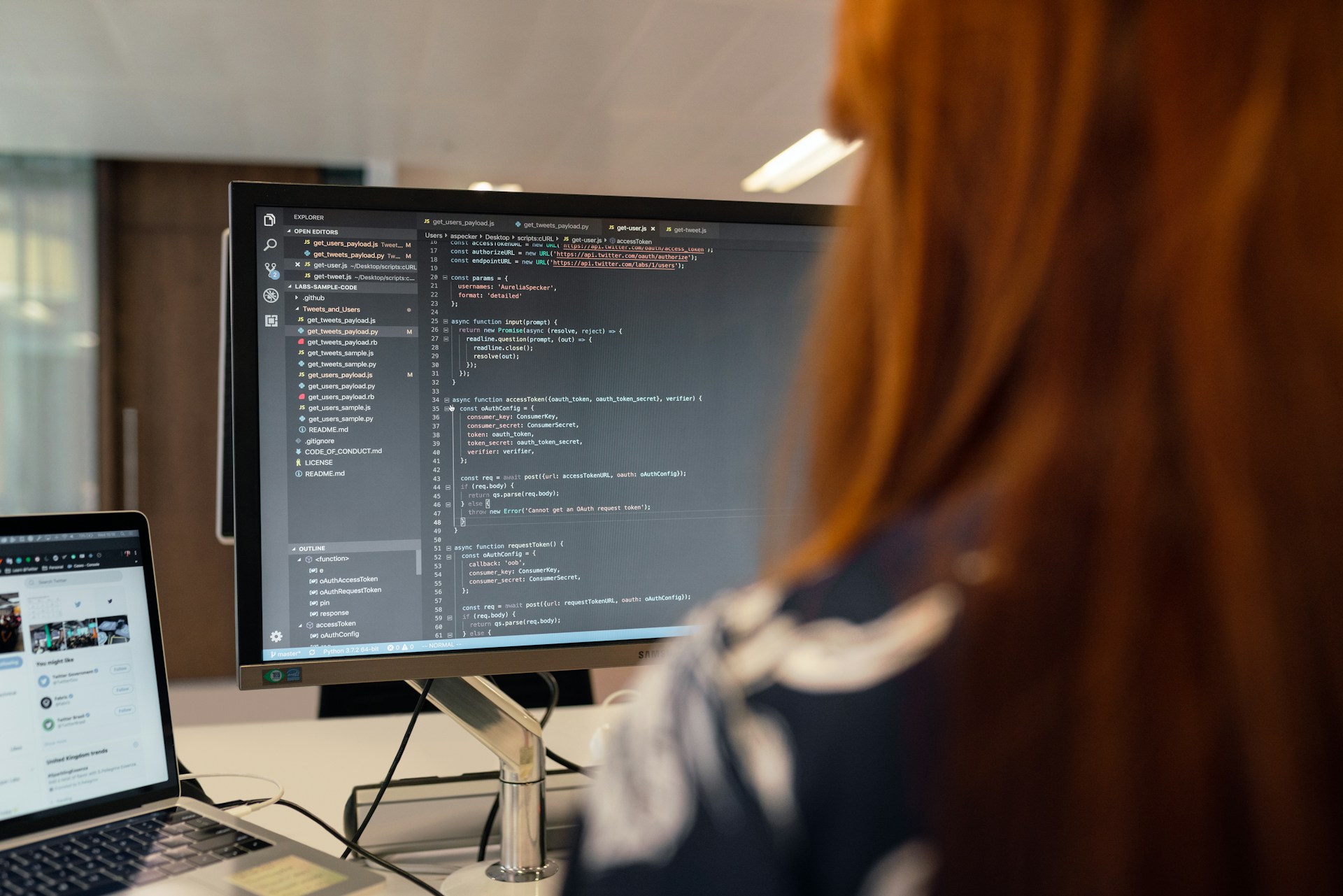 An engineer at a dual-monitor desk, warm lamp light, working through a codebase — the forward-deployed reality behind lab theory.